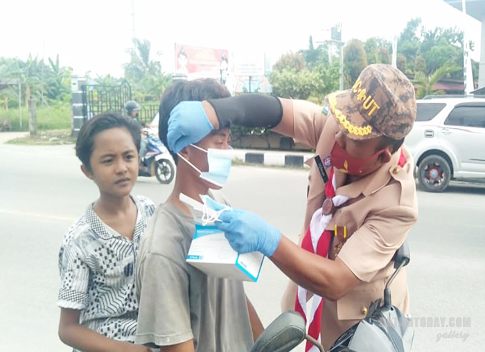 Ikhwan, Bendahara Umum Kwarcab Pramuka Kabupaten Karimun saat memakaikan masker kepada anak-anak